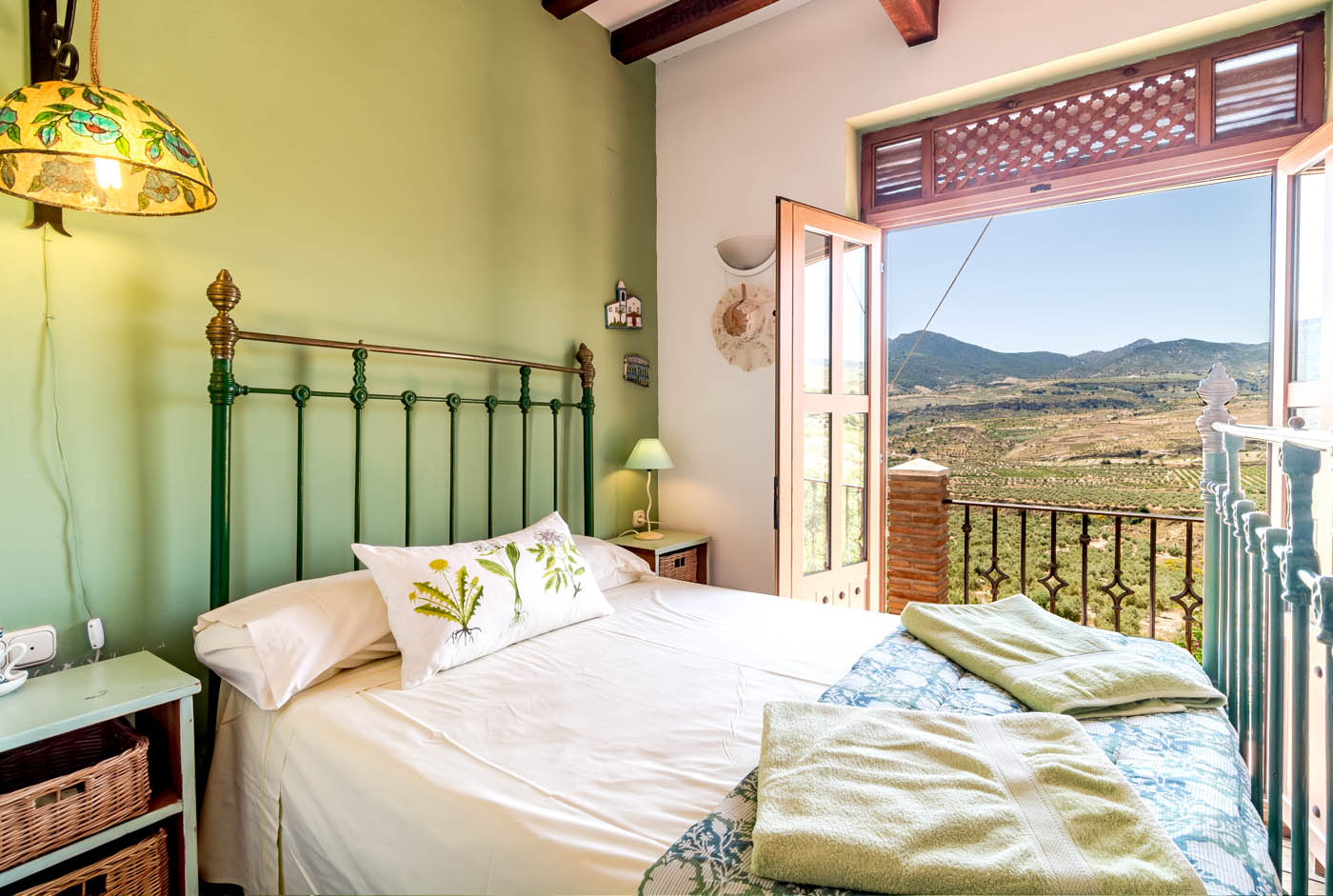 Habitación en el primer piso con cama doble y balcón.